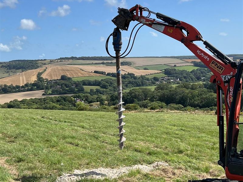 Auger rig boring a borehole into the ground on a hillside site