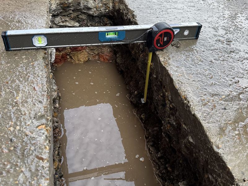 Recording trial pit dimensions with a spirit level and tape measure