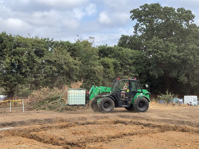 Telehandler moving water containers into position on a new-build development site