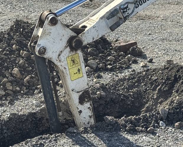 Excavator digging a trial pit on a hardstanding site